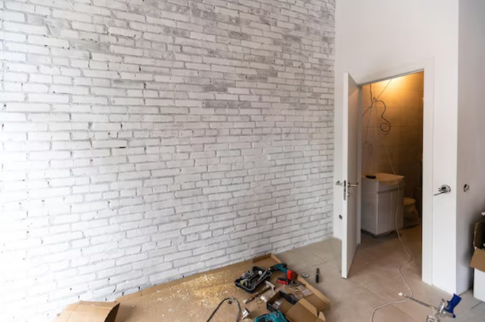 Reforma integral en piso de Valencia con pared de ladrillo blanco y colocación de puertas nuevas.