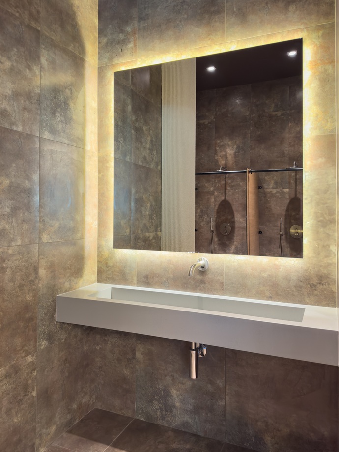 Reforma de baño gama alta con grifería empotrada, espejo retroiluminado y revestimiento porcelánico exclusivo.