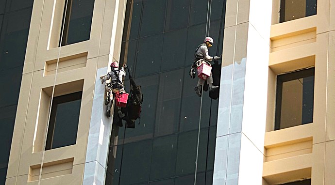 Equipo de pintores verticales  de Europa 9 aplicando revestimiento protector en fachada de gran altura mediante técnicas de descuelgue sin andamios.