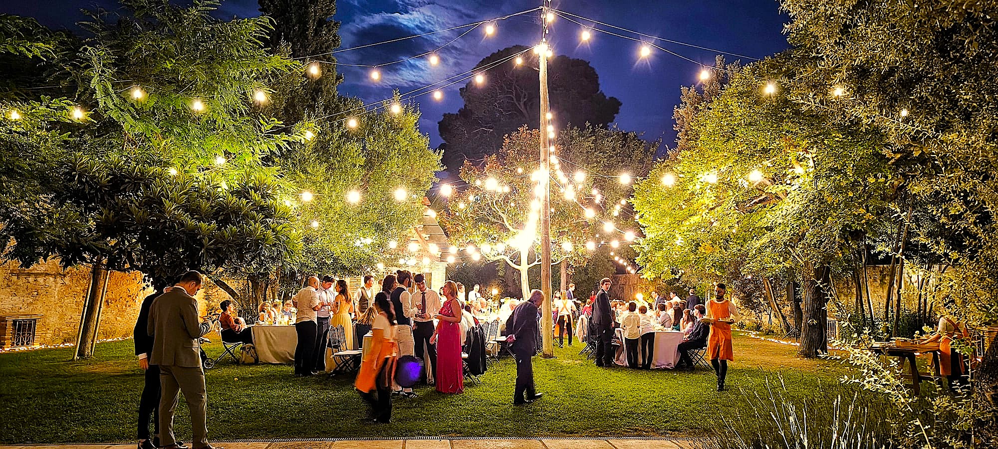 Montaje de guirnaldas de luz cálida para banquete de comunión al aire libre por Discotecas Móviles Innovagroup.