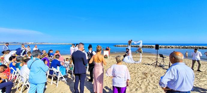 Pareja de novios caminando por jardín exterior de día, sosteniendo bengalas de humo de colores azul y rosa, creando un efecto visual vibrante para fotografía nupcial.