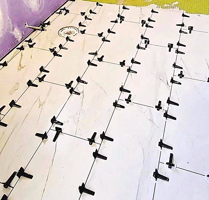 Suelo porcelánico marmoleado en proceso de instalación con sistema de nivelación profesional anti-cejas.