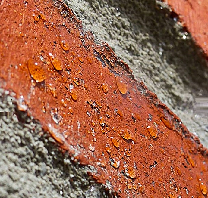 Demostración de efecto hidrófugo en fachada vertical tratada, donde el agua es repelida molecularmente sin formar película.