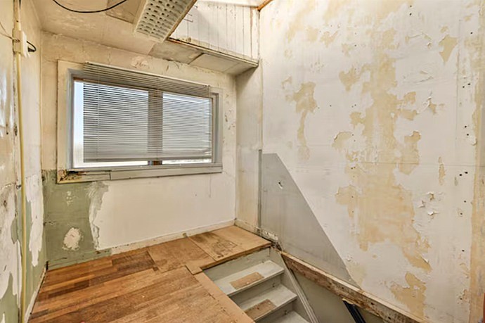 Vista de sala en Valencia con pintura desconchada y madera antigua, antes de la intervención integral.