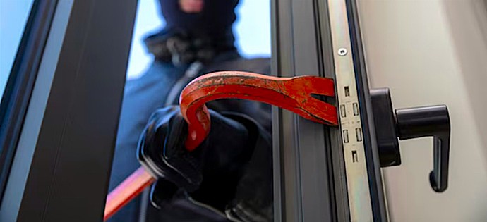 Ataque agresivo sobre el perfil de una puerta utilizando una palanca metálica roja