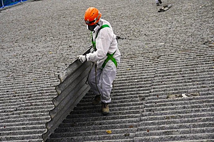 Técnicos cualificados empleando sistemas de cuerda para retirar placa de fibrocemento.