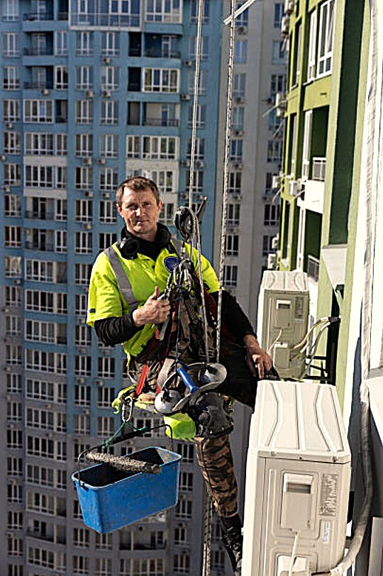 Técnico cualificado realizando trabajos verticales en fachada.