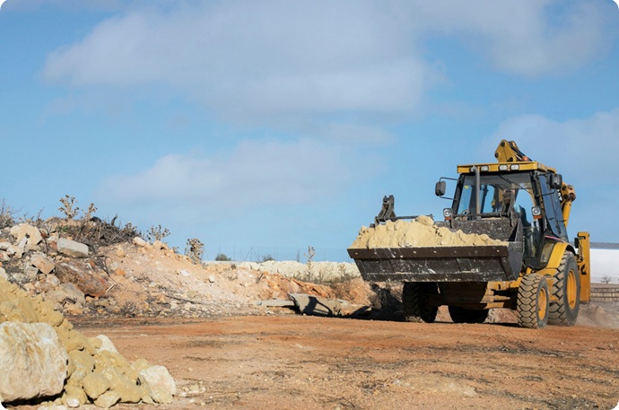 Maquinaria pesada realizando movimiento de tierras y extracción masiva en terreno industrial.