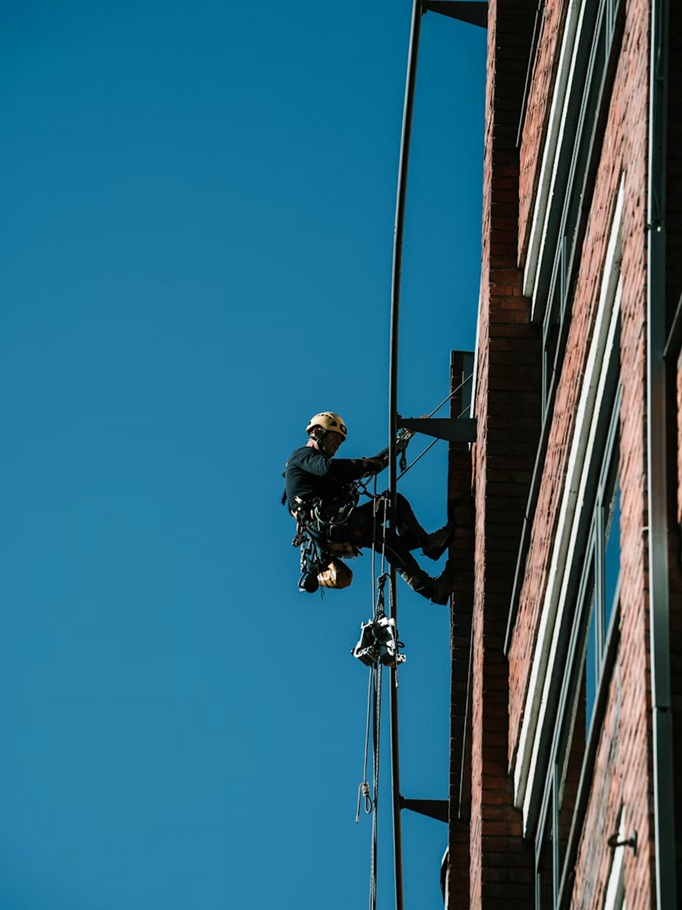 Técnico especialista en trabajos verticales ejecutando la consolidación de una fachada mediante cuerdas.