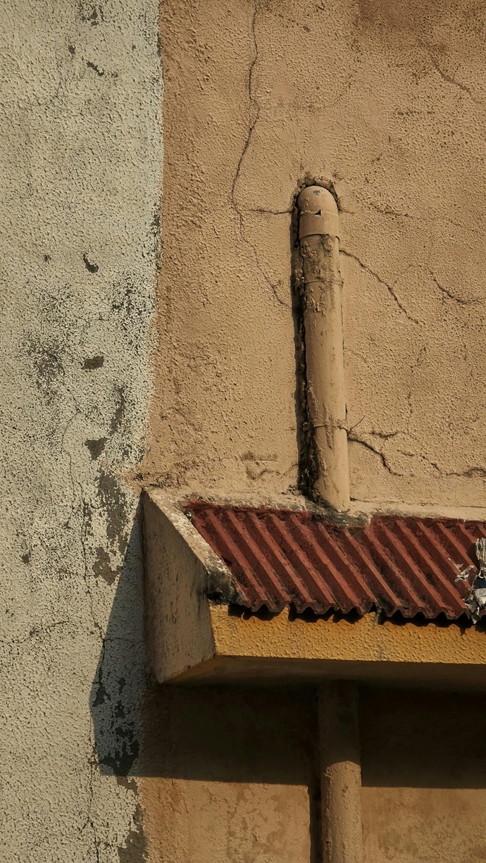 Red de bajante de saneamiento exterior en la fachada de un establecimiento comercial en Tenerife Sur.