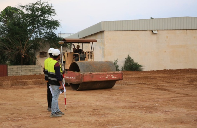 Técnicos de Adisa supervisando la nivelación y compactado de suelo mediante cilindros vibratorios en obra industrial.