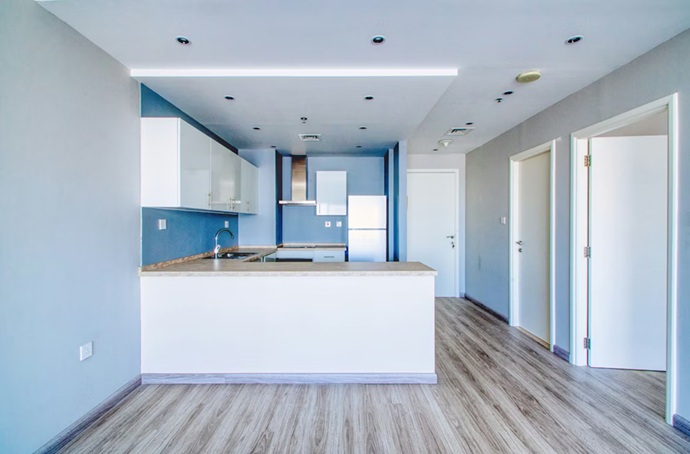 Reforma de cocina de concepto abierto con mobiliario minimalista blanco, contraste de salpicadero cerámico oscuro y luminarias de suspensión de aire industrial sobre península.
