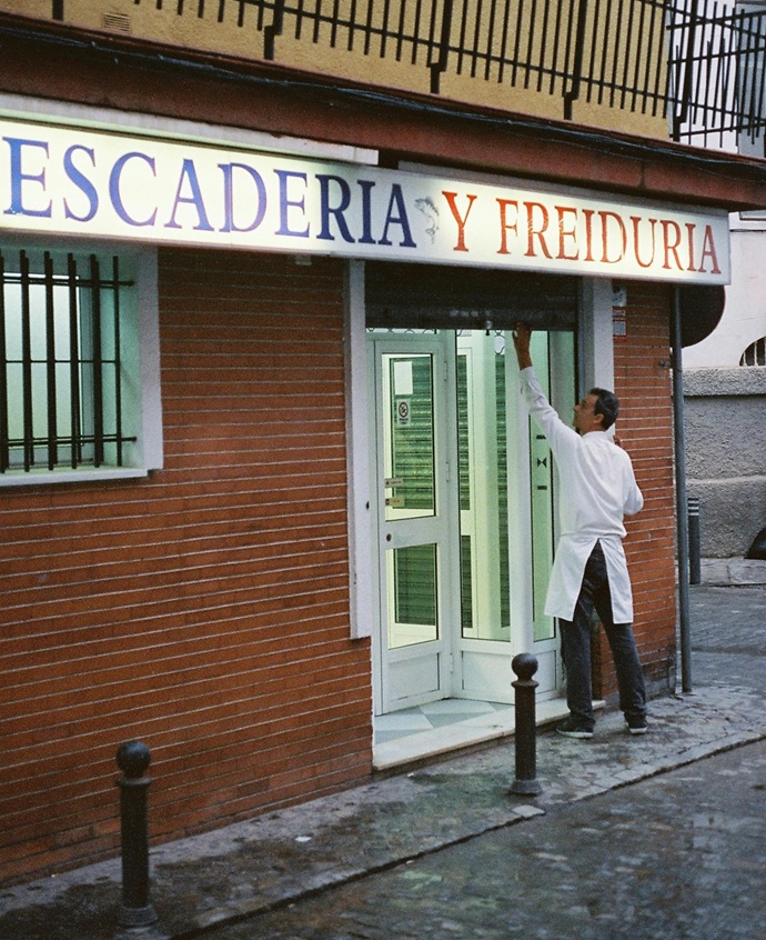 Dueño de comercio de alimentación operando el cierre de su persiana en Cornellà