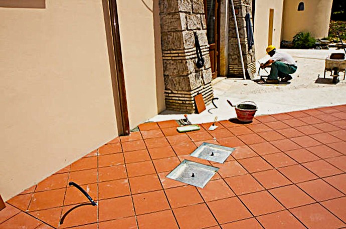 Maestro de obra ajustando pavimentación de terracota con inclinación hidráulica optimizada.