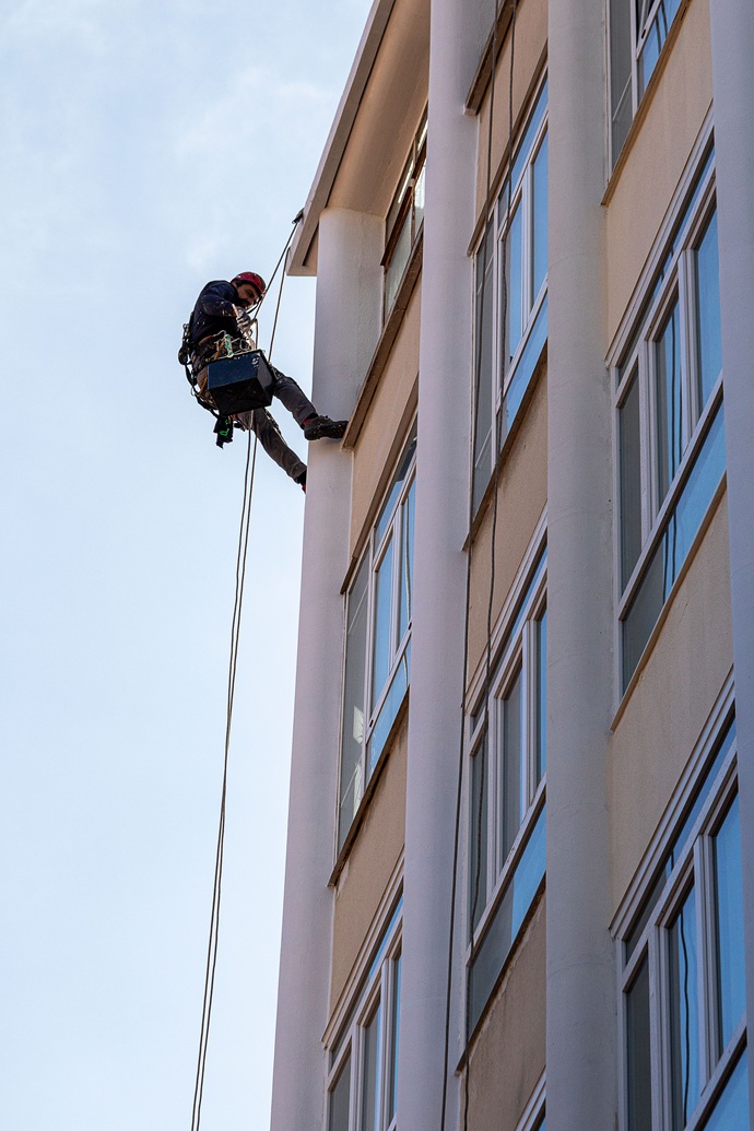 Técnico veterano en vertical instalando conducciones isofónicas sin andamiaje ruidoso)