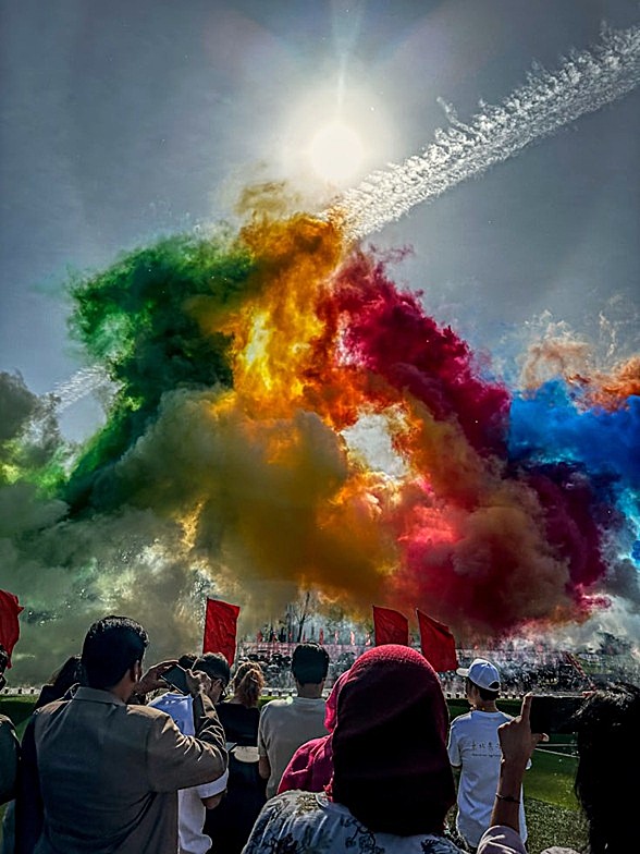 Explosión masiva de humo arcoíris proyectada al cielo durante una ceremonia al aire libre gestionada por Innovagroup.