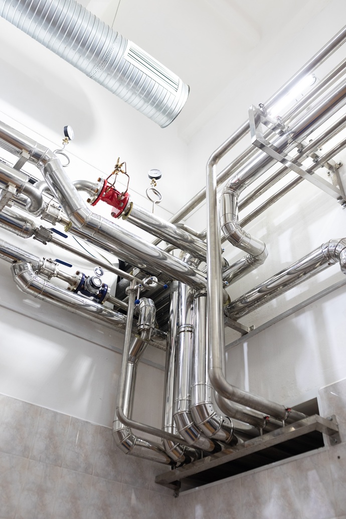 Estructura técnica de tuberías de acero inoxidable y manómetros en una sala de máquinas hotelera de Tenerife Sur.
