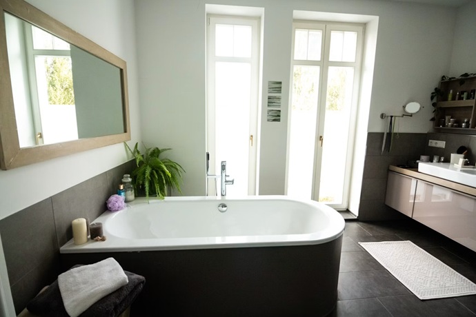 Reconfiguración de aseo de diseño minimalista con amplios ventanales y bañera de faldón oscuro en Santiago del Teide.