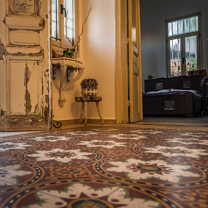 Habitación de vivienda clásica en Barcelona con suelo hidráulico modernista y puerta de madera restaurada.